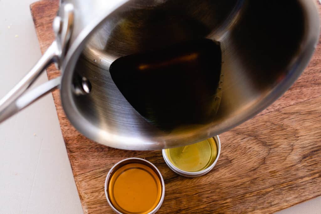 Pouring the melted ingredients from the saucepan into the small lip balm tins.