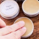 Dabbing two fingers into a vegan lip balm tin.