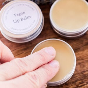 Dabbing two fingers into a vegan lip balm tin.