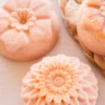 Turmeric soap bars with flower top designs drying on white table.