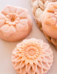 Turmeric soap bars with flower top designs drying on white table.
