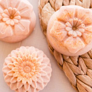 Flower shaped turmeric soap bars on a wicker mat.