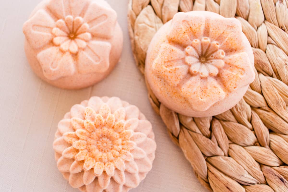 Flower shaped turmeric soap bars on a wicker mat.