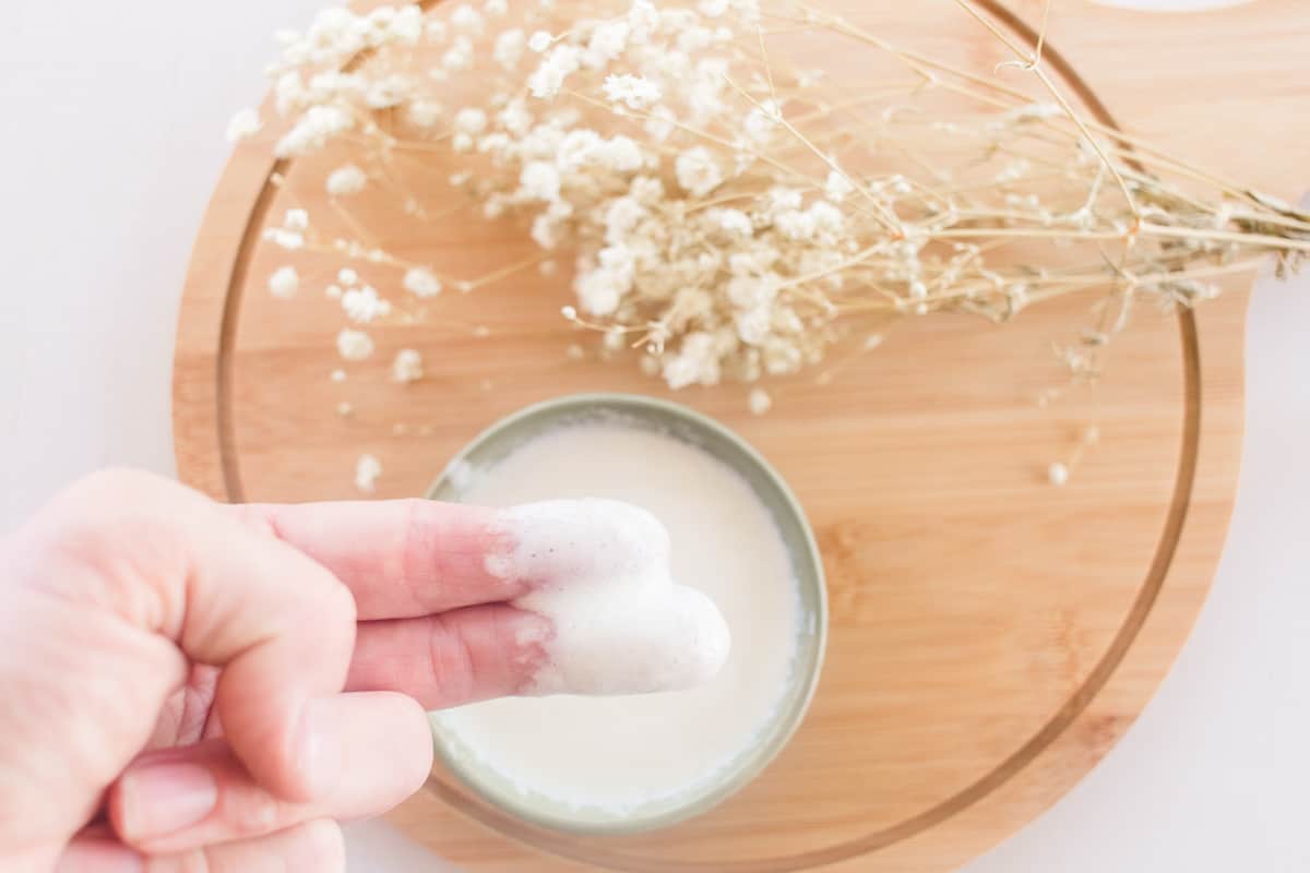 Two fingers scooping out a homemade conditioner.