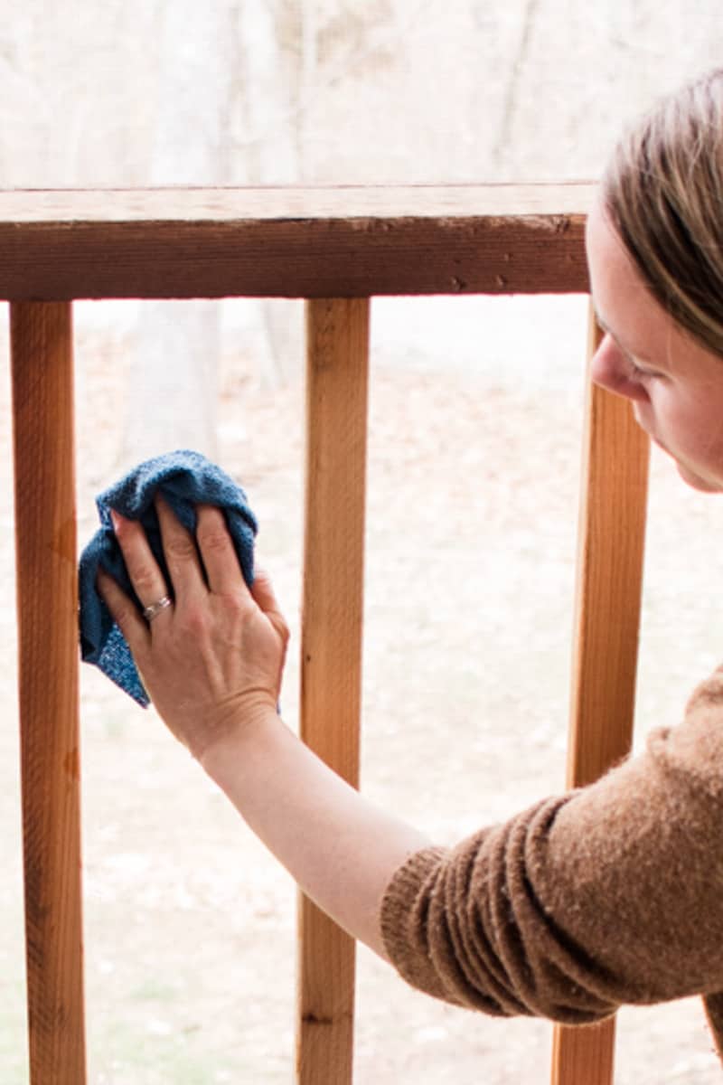 Wiping down a porch screen using warm soapy water and a gentle cloth.