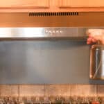 Spraying a stainless steel range hood with vinegar.