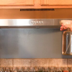 Spraying a stainless steel range hood with vinegar.