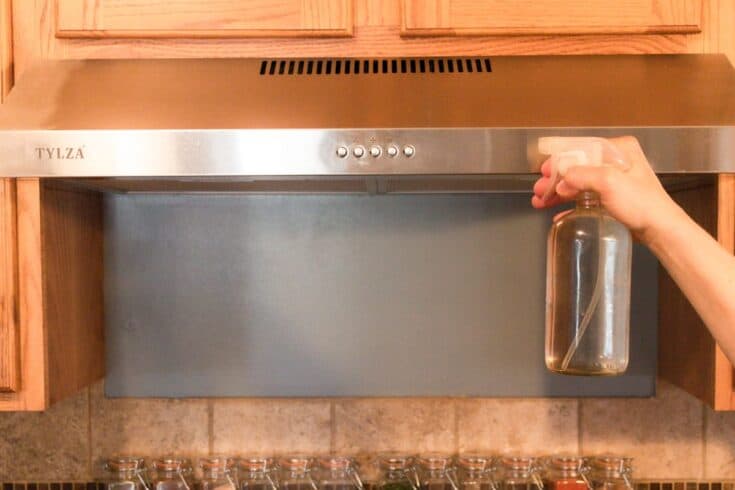 Spraying a stainless steel range hood with vinegar.