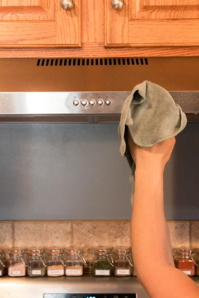 Cleaning a range hood with a cloth. 