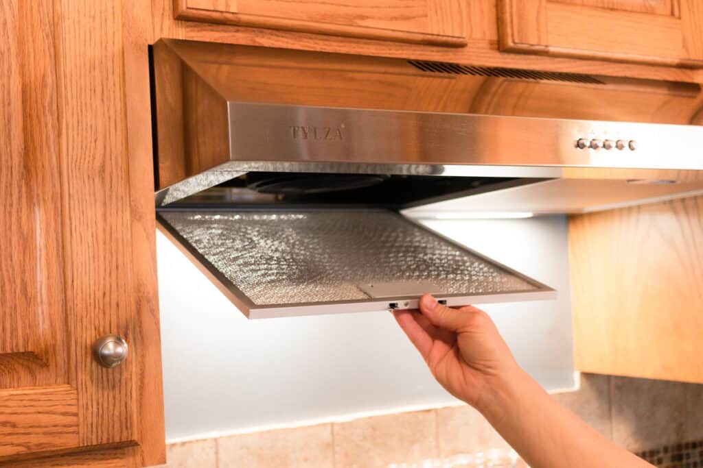 Replacing a clean range hood filter. 