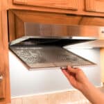 Removing a filter from a stainless steel range hood.