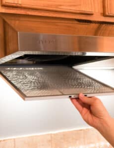 Removing a filter from a stainless steel range hood.