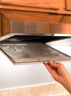 Removing a filter from a stainless steel range hood.