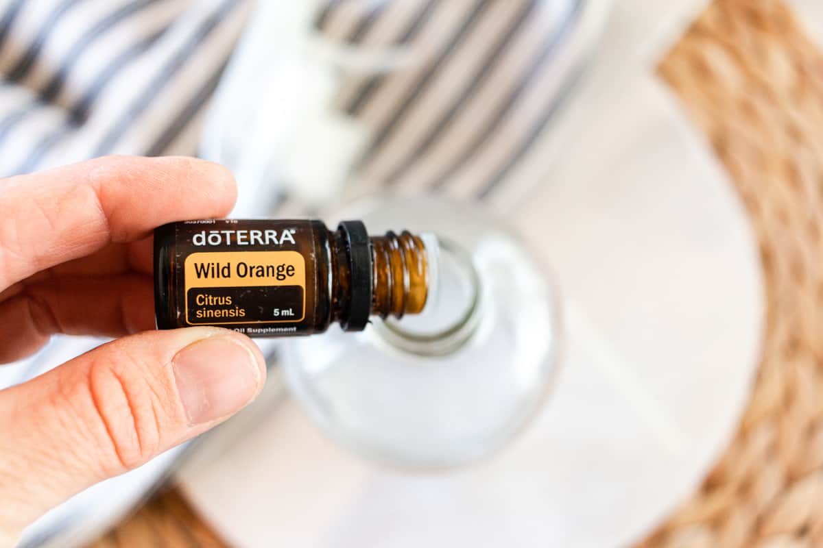 Adding orange essential oil to homemade bathroom cleaner. 