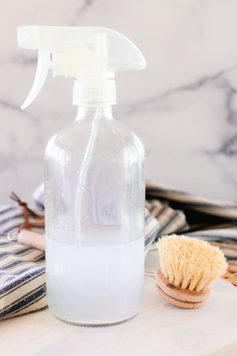 A bottle of homemade bathroom cleaner with scrub brush. 