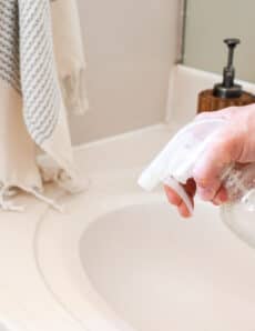 Using a homemade bathroom surface cleaner on a white vanity.