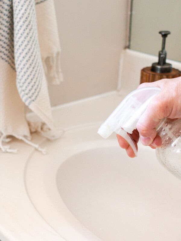 Using a homemade bathroom surface cleaner on a white vanity.