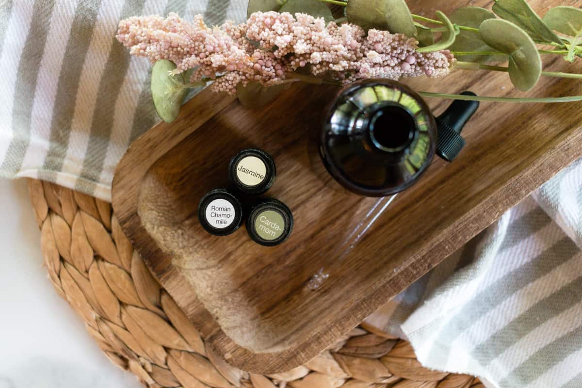 Essential oils x 3 and a bottle of DIY massage oil on a wooden board. 
