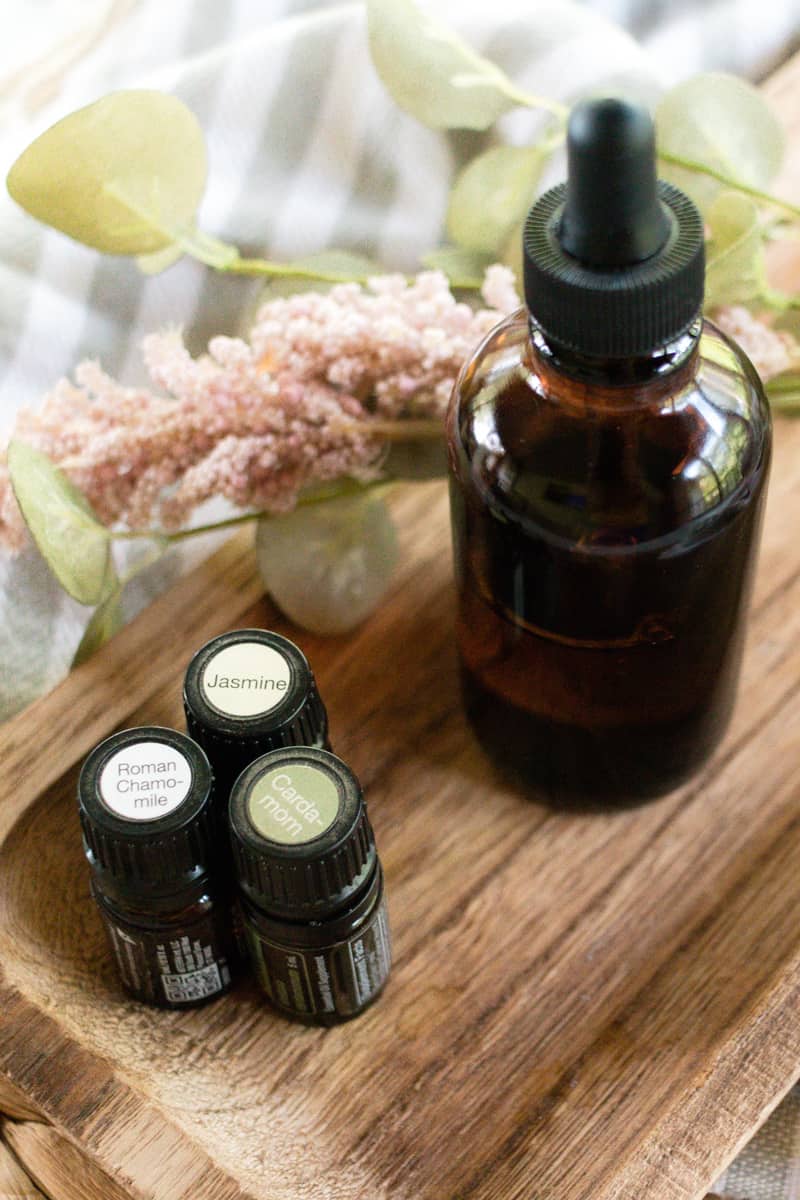 Essential oils x 3 and a bottle of massage oil on a wooden board. 