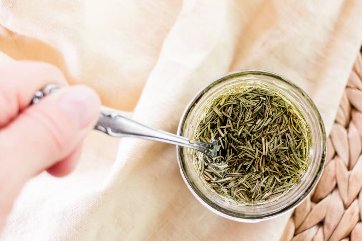 Pressing the rosemary leaves into the olive oil before placing it in the windowsill to infuse.