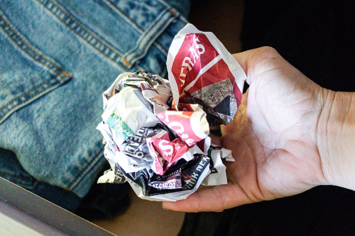 Crumpled newspaper being placed in a dresser drawer to absorb odors.