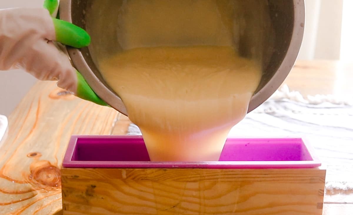 Pouring the melted cold process shea butter soap into a soap mold to cure.
