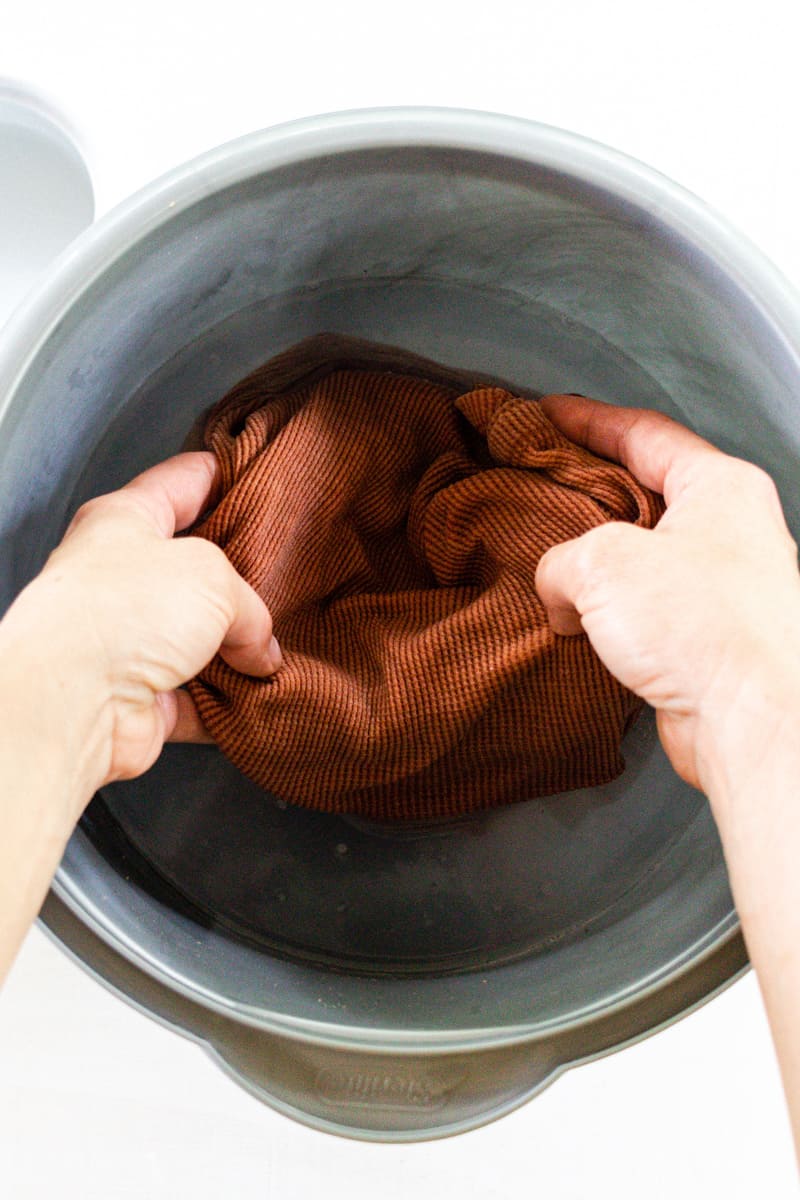 Soaking clothing in a bowl of mold remover. 