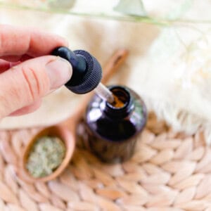 Adding the homemade rosemary oil to a glass jar for storage.