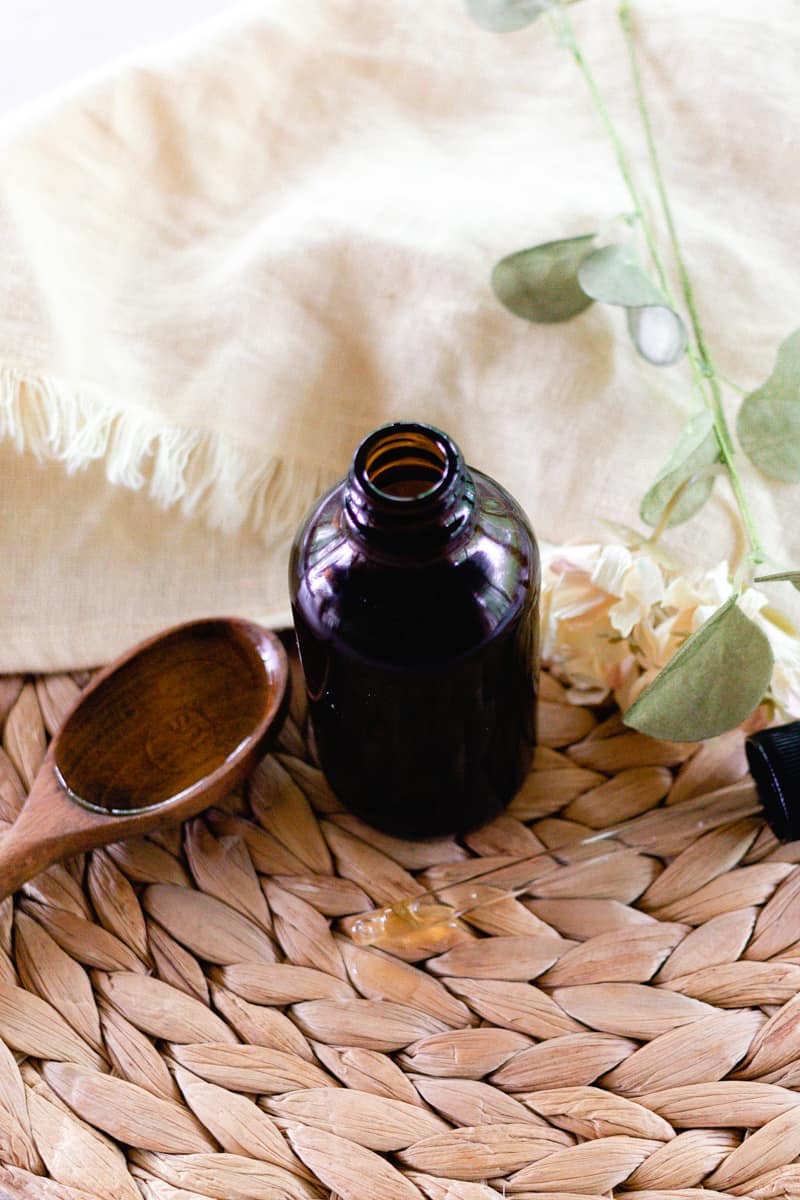 A glass bottle with spoonful of oil nearby. 