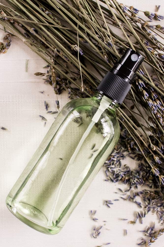 A bottle of body mist with lavender sprigs nearby. 