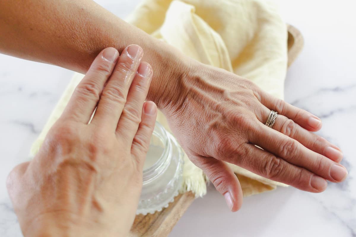 Rubbing a tanning oil onto the arm.
