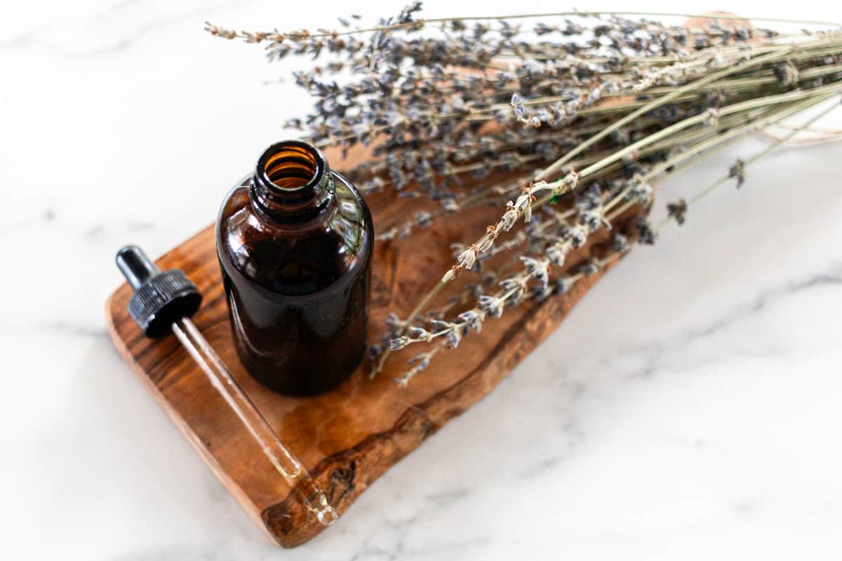 A homemade tanning oil in a glass dropper bottle with the dropper next to it.