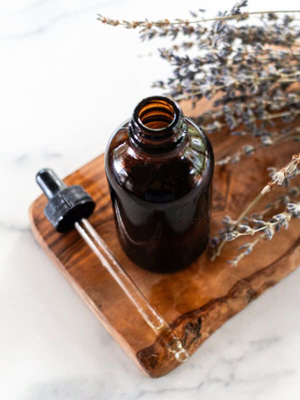 Tanning oil in a glass dropper bottle on a white marble.