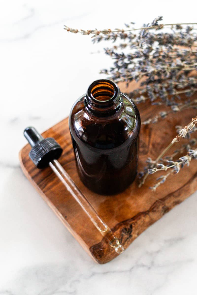 Tanning oil in a glass dropper bottle on a white marble.