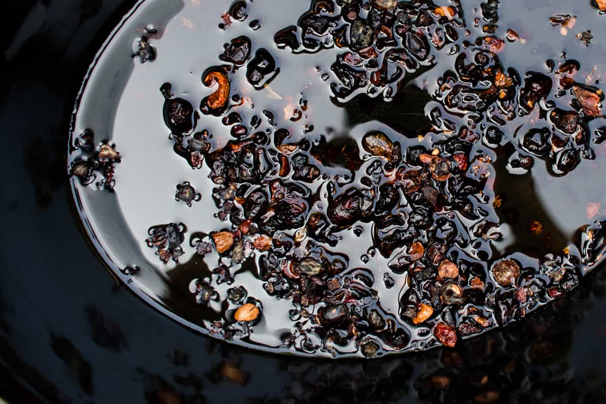 Adding olive oil to the crockpot with rosehips.