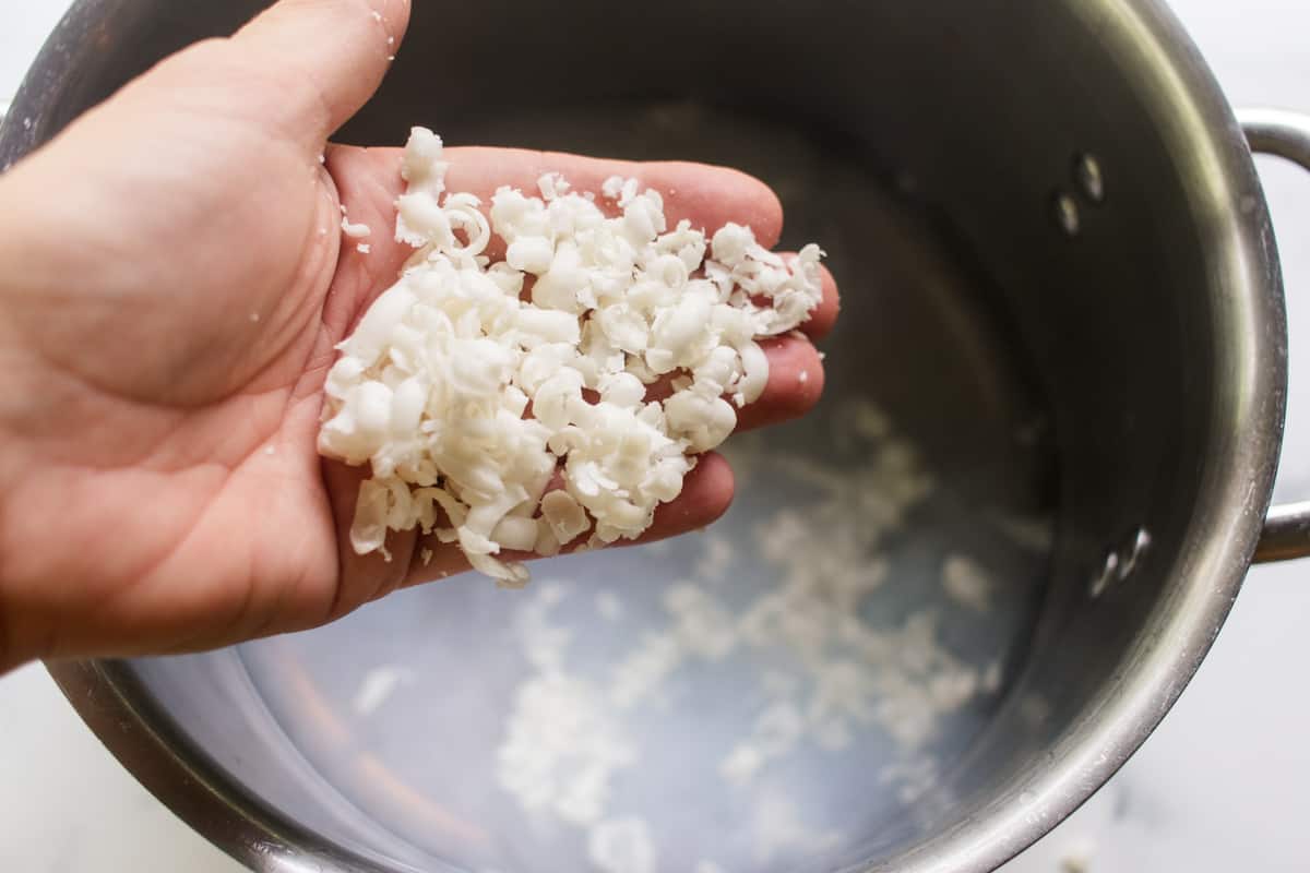 Adding the shredded soap bar to a pot of boiling water.