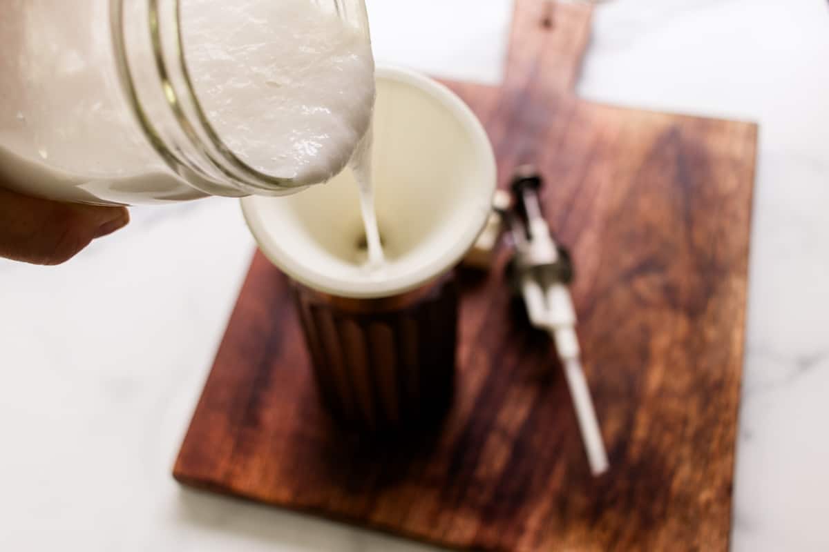 Pouring the freshly made soap into a dispenser using a funnel.