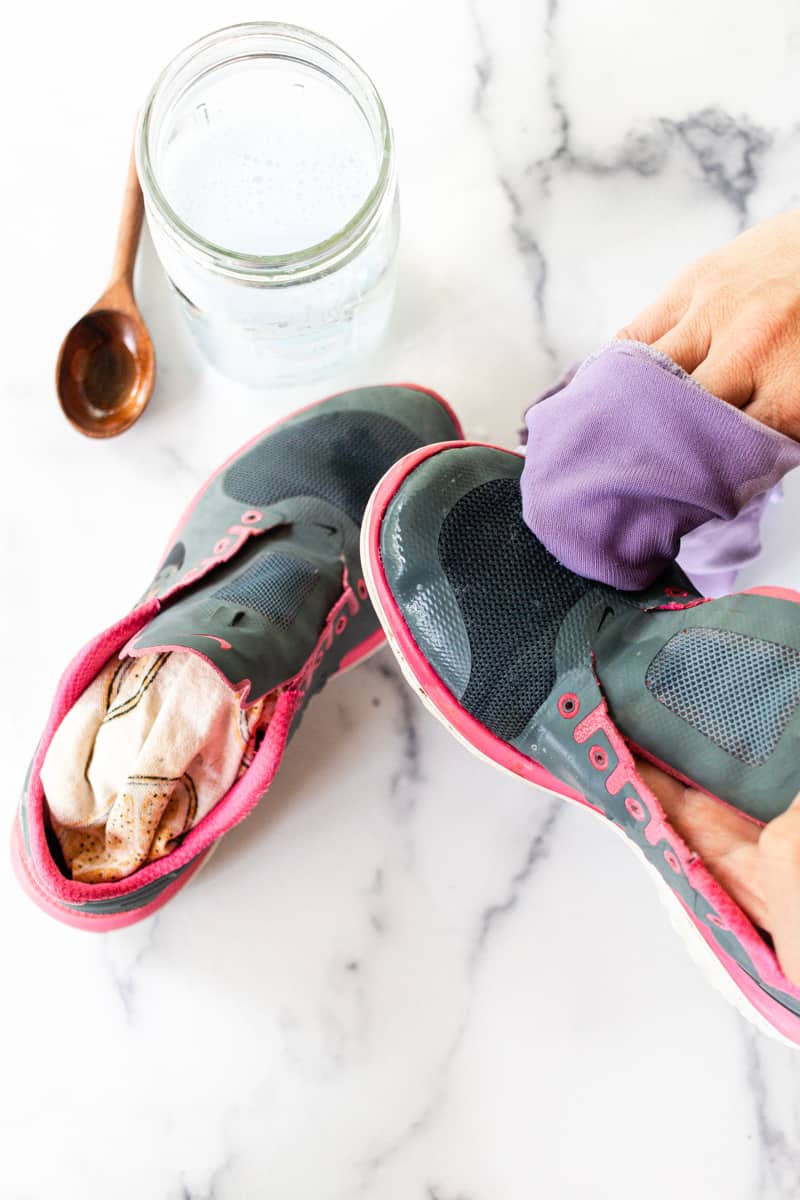 Scrubbing mesh shoes with a soapy cloth.