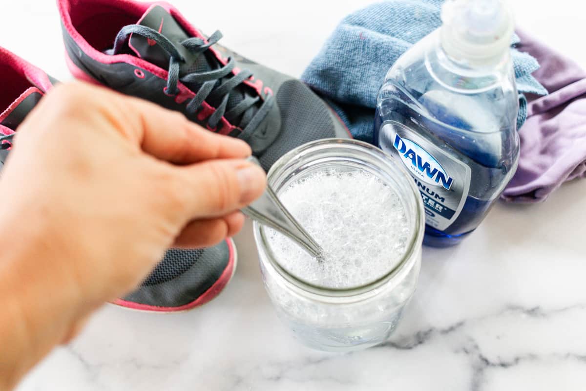 Mixing soap into warm water to clean dirty running shoes.