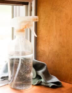 A mold killer for cleaning window sills sitting on a wooden window sill.