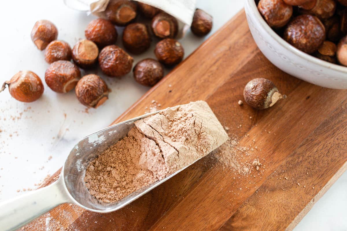 Fresh ground soap nut powder on a wooden board with whole soap nuts around it.