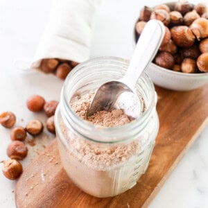 Soap nut laundry detergent in a glass storage container on a wooden shelf.