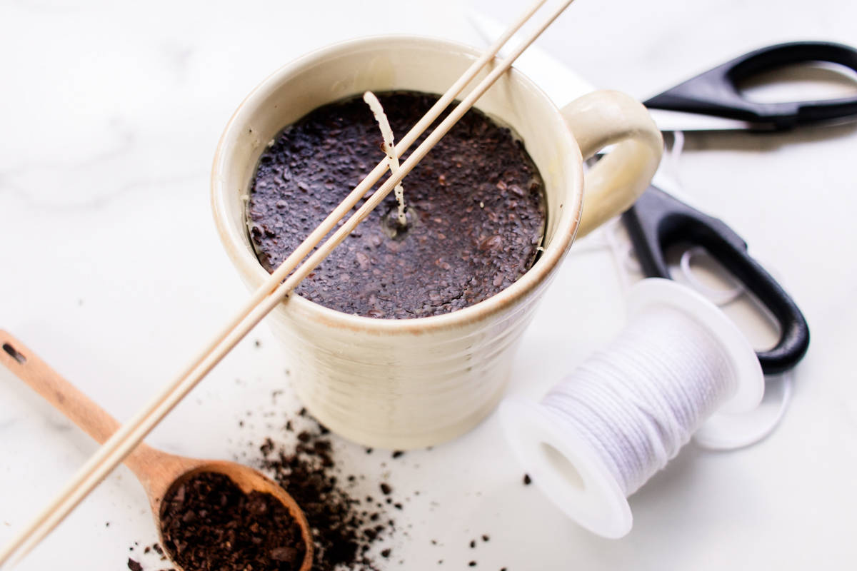 Securing the wick in the center of the mug.