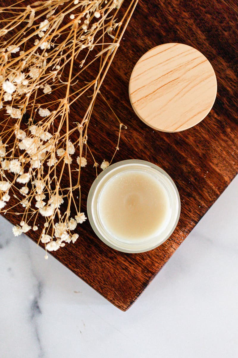 DIY cleansing balm cooling in a glass jar with a wooden lid.