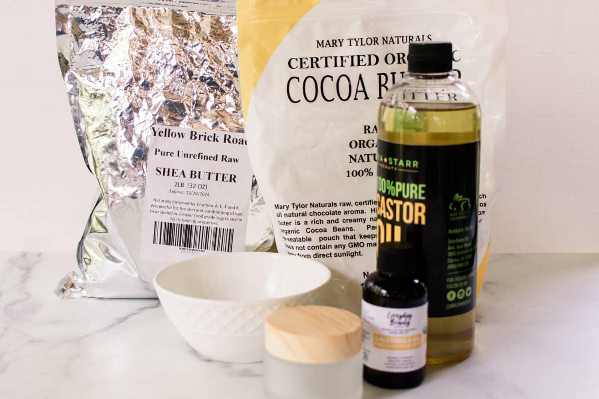 Cleansing balm ingredients on a white marble table.