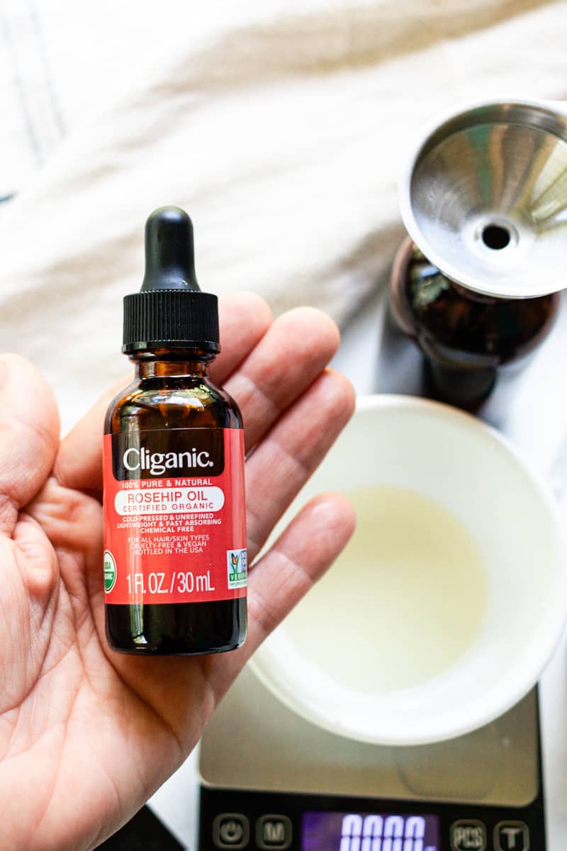 Holding rosehip oil over a bowl.