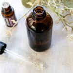 A DIY facial oil in an amber dropper bottle on a wooden table.