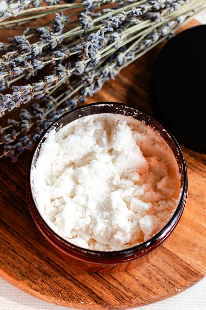 A homemade coconut milk bath in a container on a wooden top.