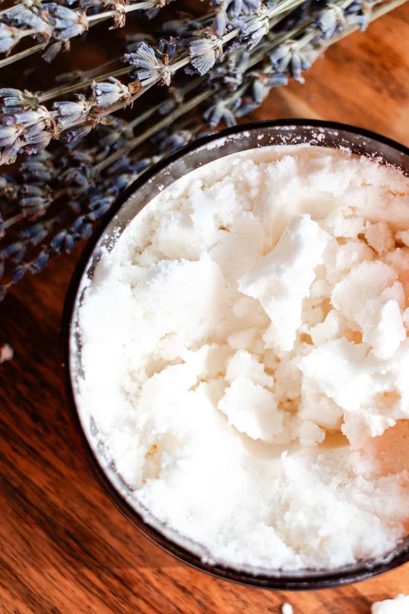 Coconut milk bath in a amber colored airtight container with lavender sprigs.