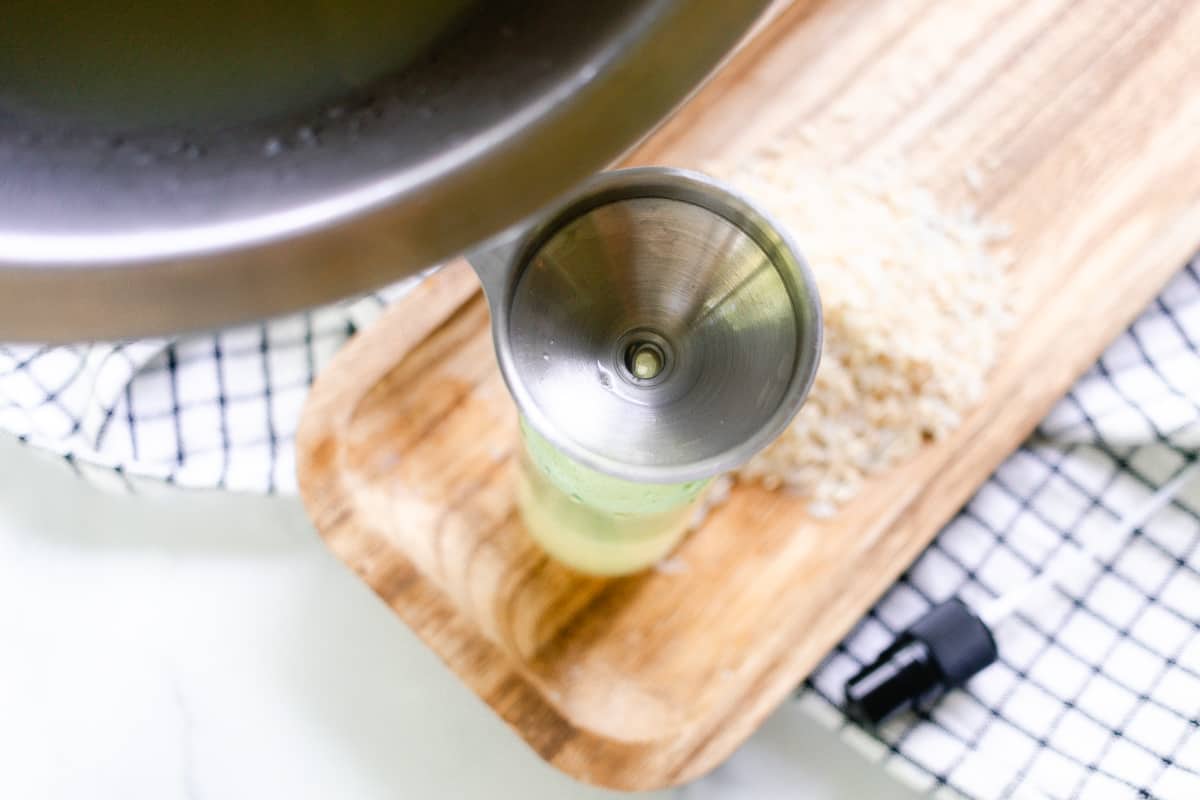 Pouring the rice water through a funnel into the spray bottle.